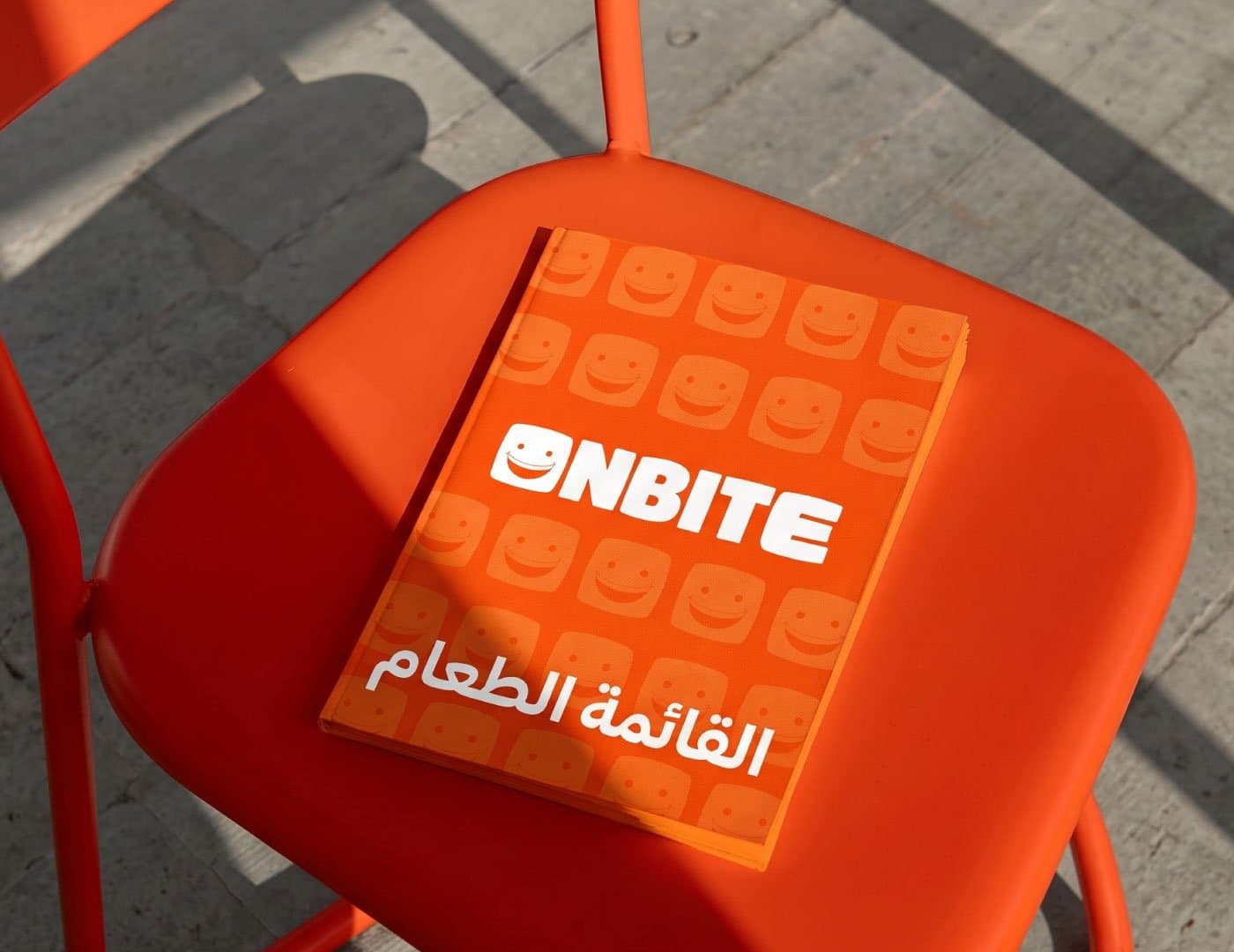 ONBITE restaurant interior featuring orange branding, digital menu boards, food displays, and branded service counter