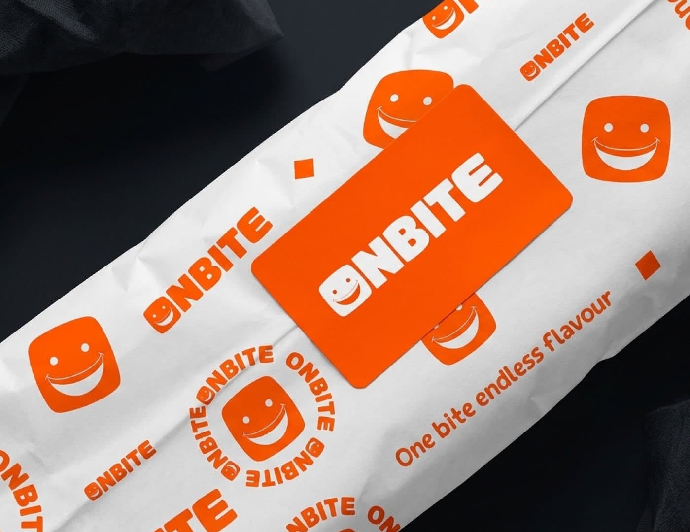 OnBite branded food wrapping paper and packaging featuring a repeating orange logo and smile icon pattern